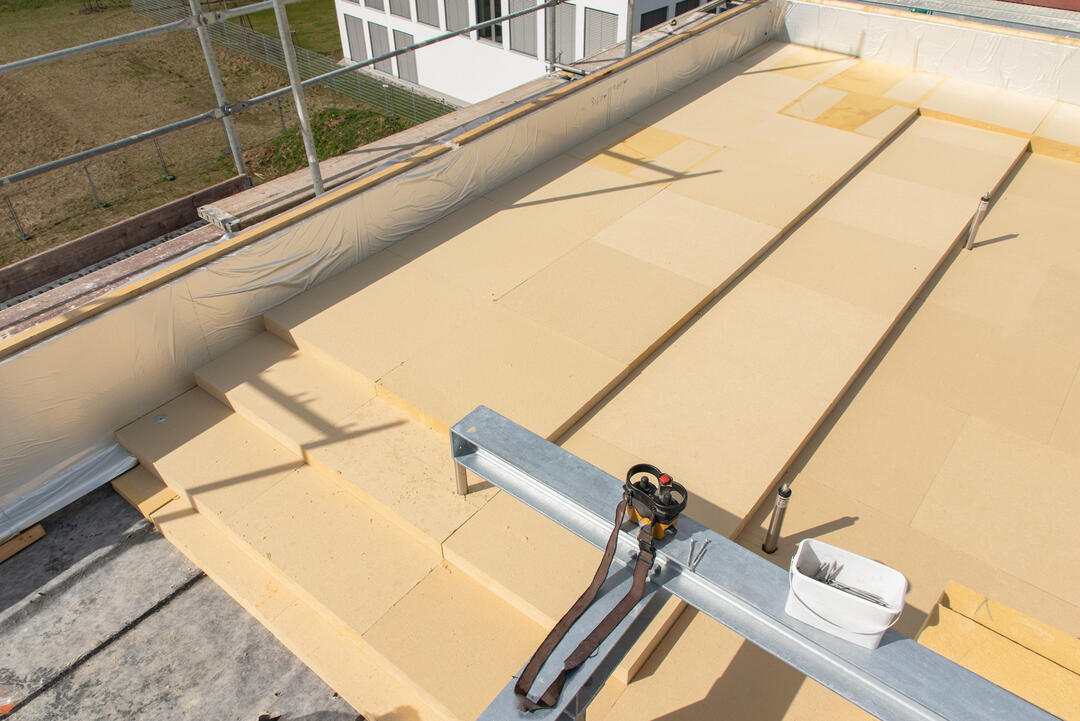 Die verlegten Holzfaserplatten auf einem Flachdach von oben fotografiert, die Sonne bescheint die Fläche.