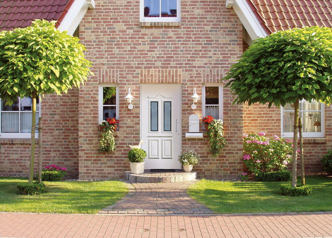 Front eines klassischen Klinker-Einfamilienhauses mit einer harmonisch dazu passenden weißen Eingangstür.