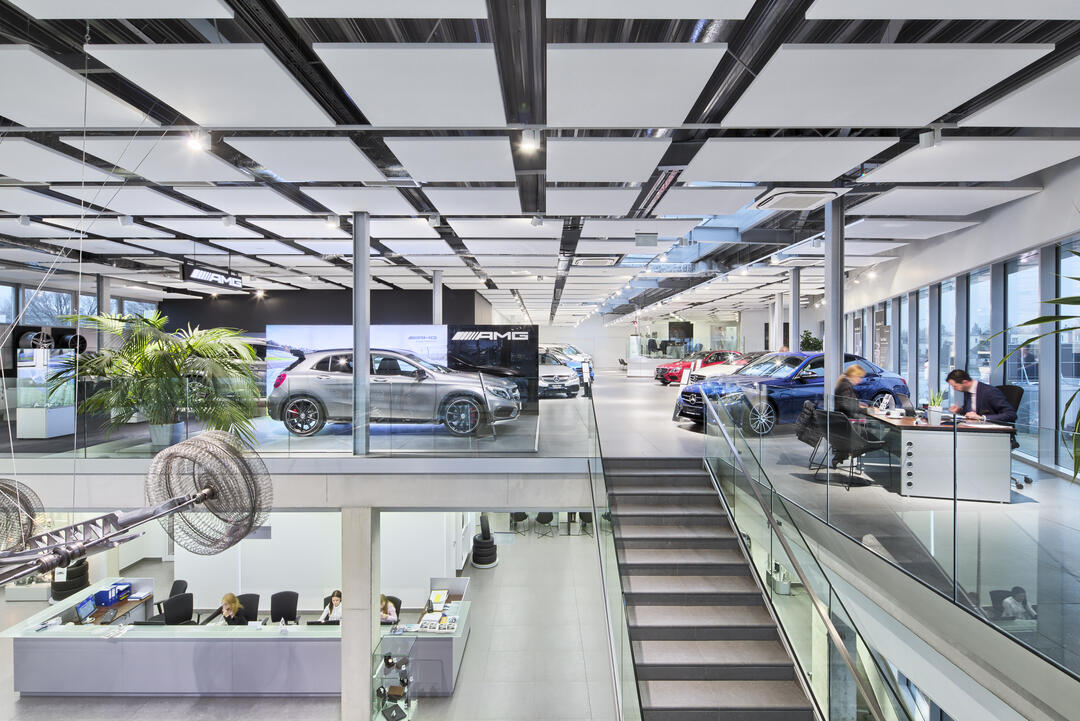 Ein zweigeschossiges, offen gehaltenes Autohaus von AMG mit quadratischen Rockfon-Elementen, die in Rasterform an der Decke montiert wurden.