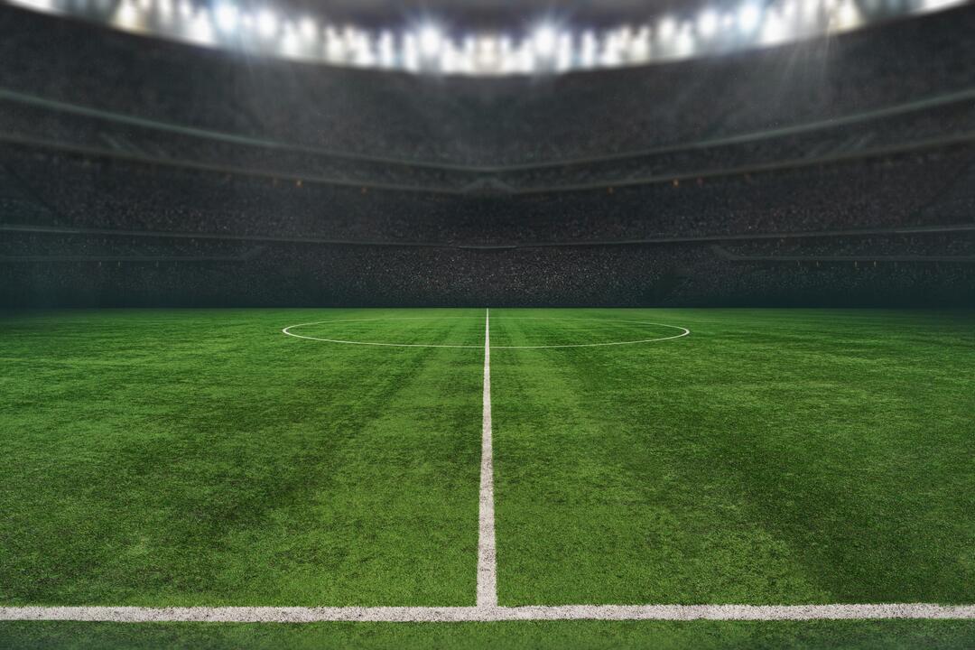 Der Rasen eines Fußballstadions, bei Nacht fotografiert und ohne Spielende, im Flutlicht.