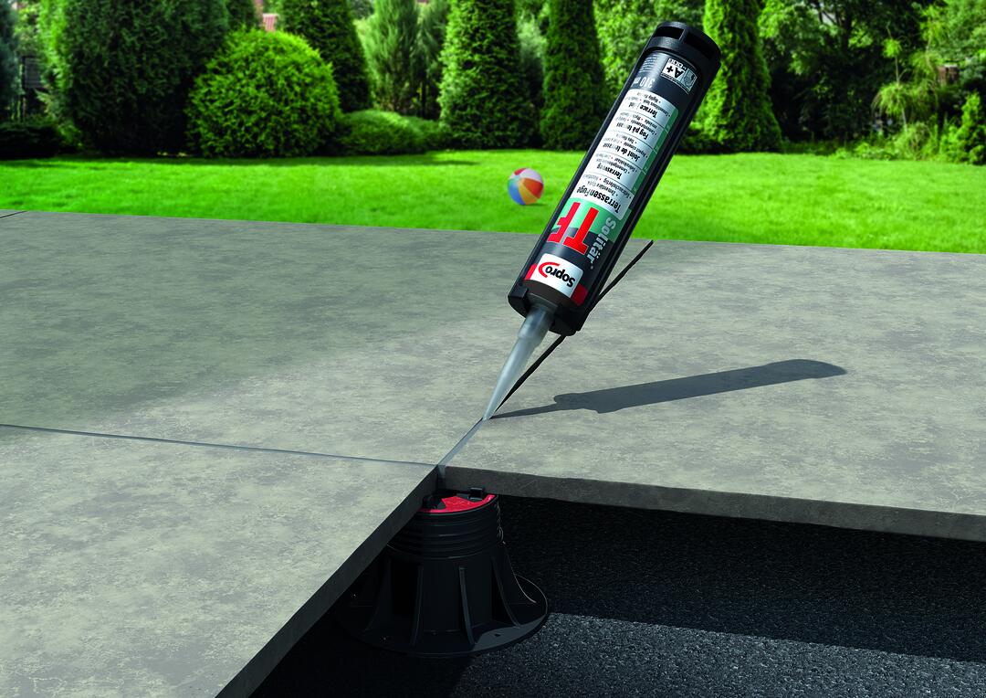 Terrasse vor einer Rasenfläche, auf der Sopro-Produkte in die Fugen zwischen den Steinplatten gegeben werden.