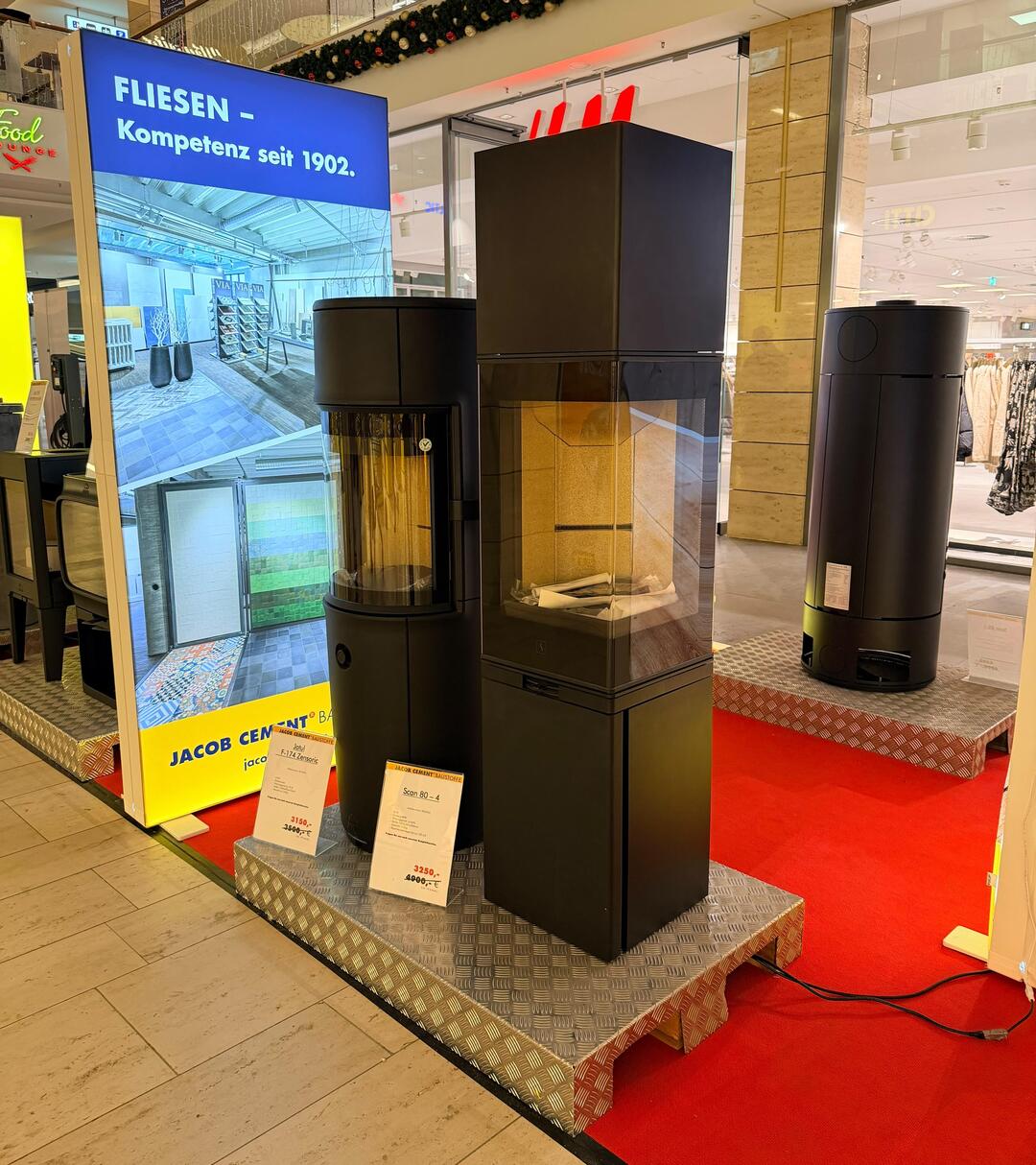 Der JACOB CEMENT-Stand auf der Bauenergie-Messe 2025 im CITTI-Park Lübeck, aus der Nähe betrachtet, mit 2 Kaminöfen nebeneinander.