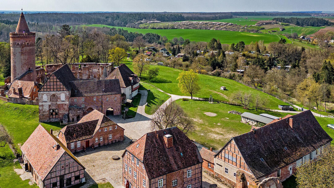 Die Burg Stargard von oben fotografiert, mit Blick auf die dahinterliegende grüne Landschaft, bis zum Horizont.