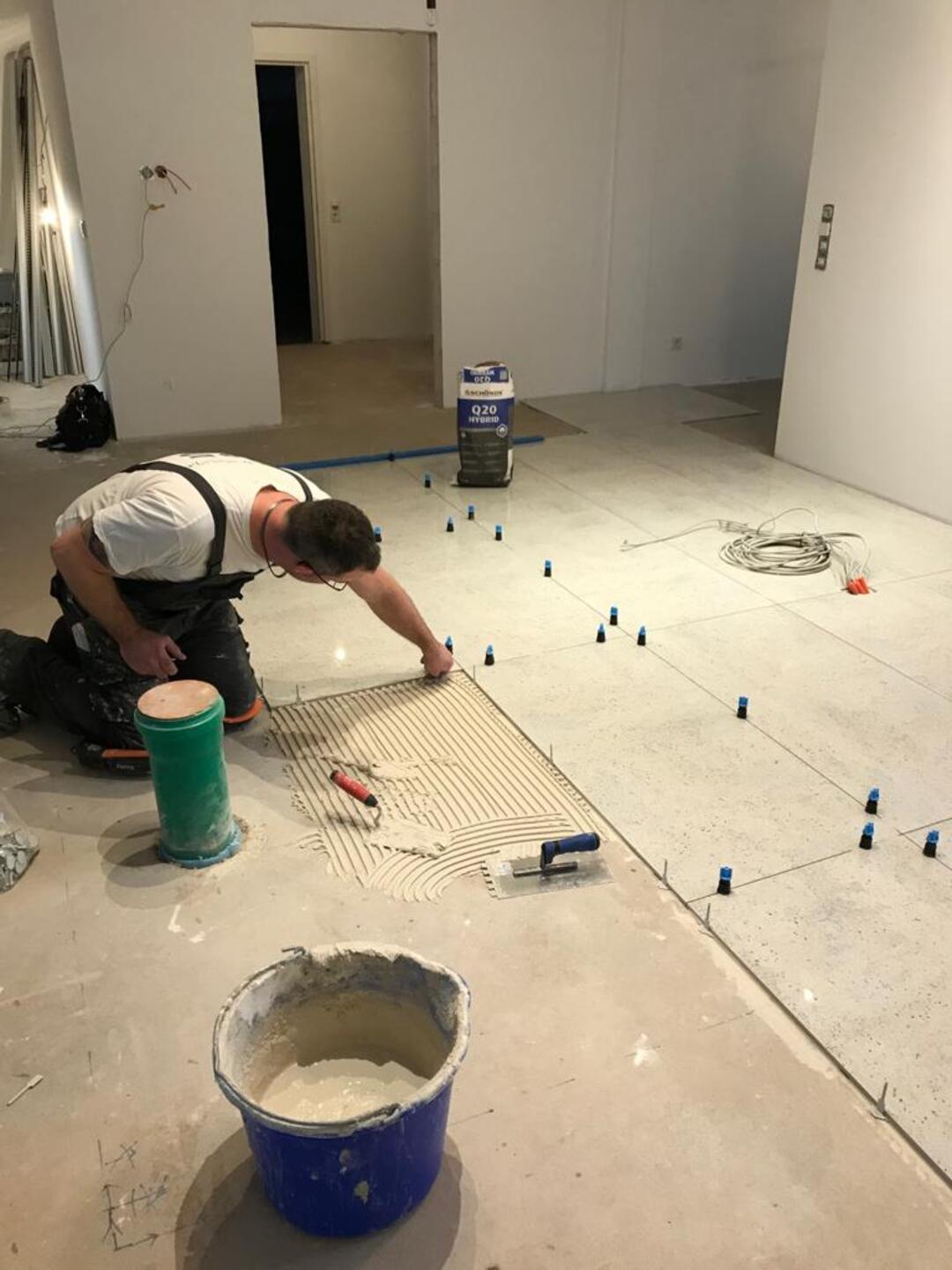 Ein Handwerker stellt am Boden einer Baustelle Distanzstifte ein.