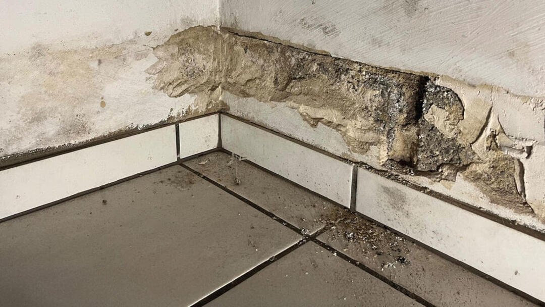 Zwei weiße Wände treffen in einer Raumecke aufeinander. Beide weisen sichtliche Spuren von Gebrauch und Verfall auf.
