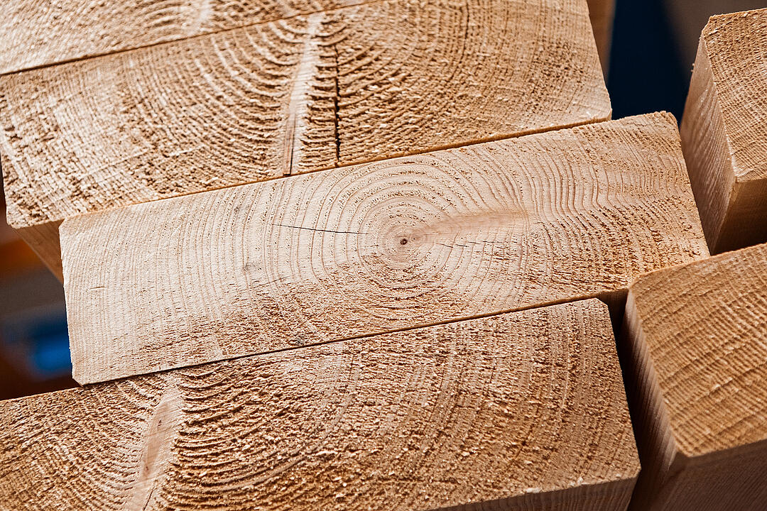 Nahaufnahme mehrerer circa fünf Zentimeter starker Holzbretter im Lager von JACOB CEMENT BAUSTOFFE