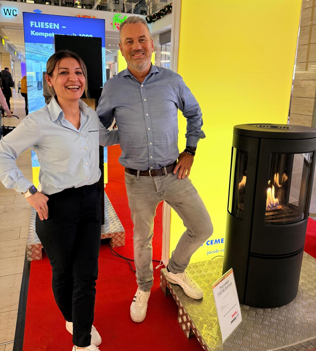 Eine Frau und ein Mann in Bürokleidung stehen lächelnd nebeneinander am JACOB CEMENT-Stand auf der Bauenergiemesse in Lübeck.