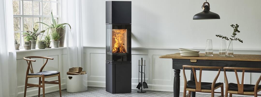 Ein schwarzer, prismatisch geformter Kamin-Ofen der Firma Jotul in einem hellen, einladenden Wohnraum.