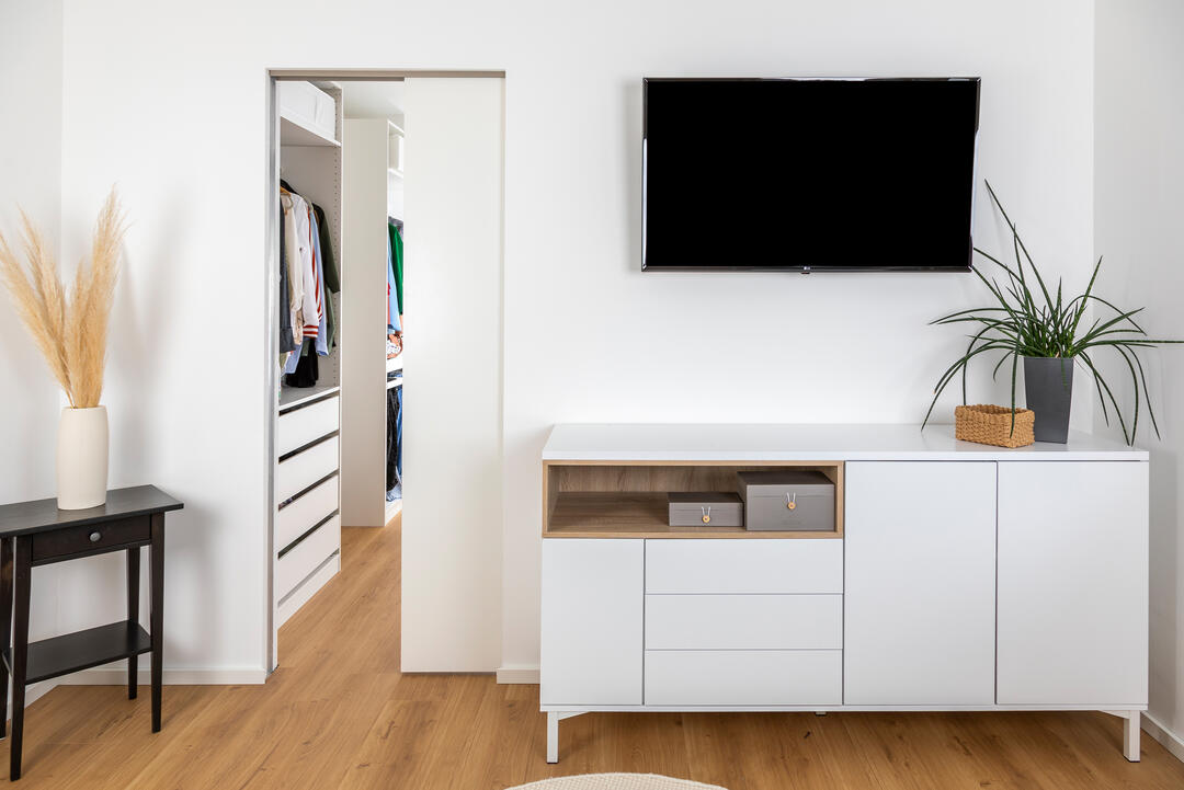 Ein helles, modernes Wohnzimmer mit einem Sideboard und einem Fernseher, daneben eine verbaute Knauf-Schiebetür in der weißen Wand.